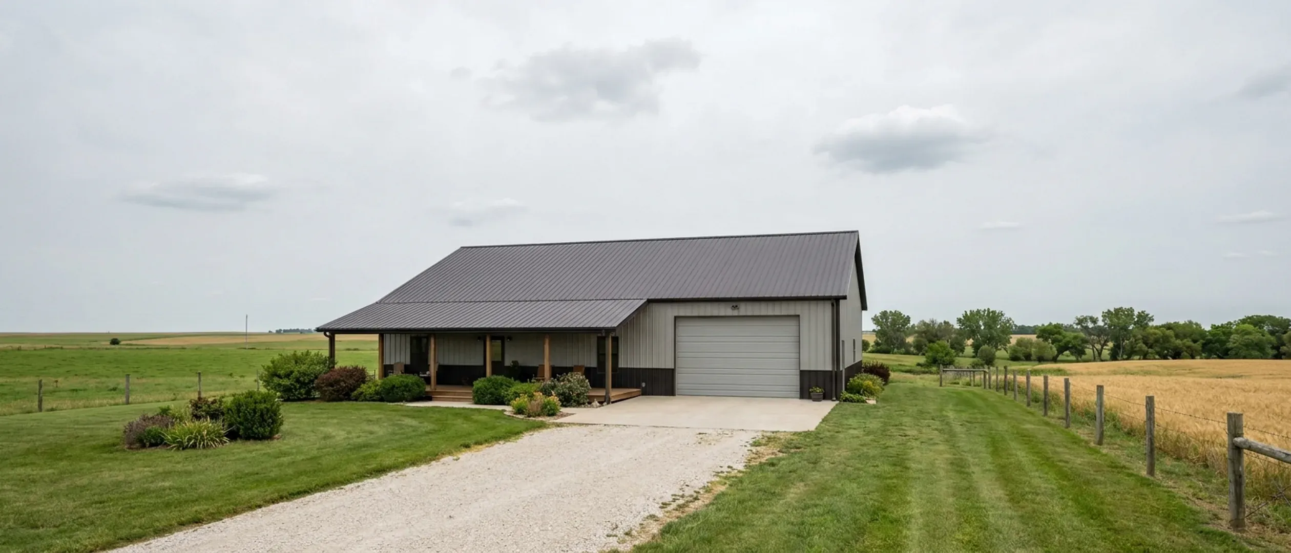 A completed barndominium with a covered entry porch and an attached shop bay, photographed in flat overcast daylight.